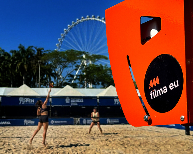 Câmeras e equipamento laranja da FilmaEu na beira da quadra de areia